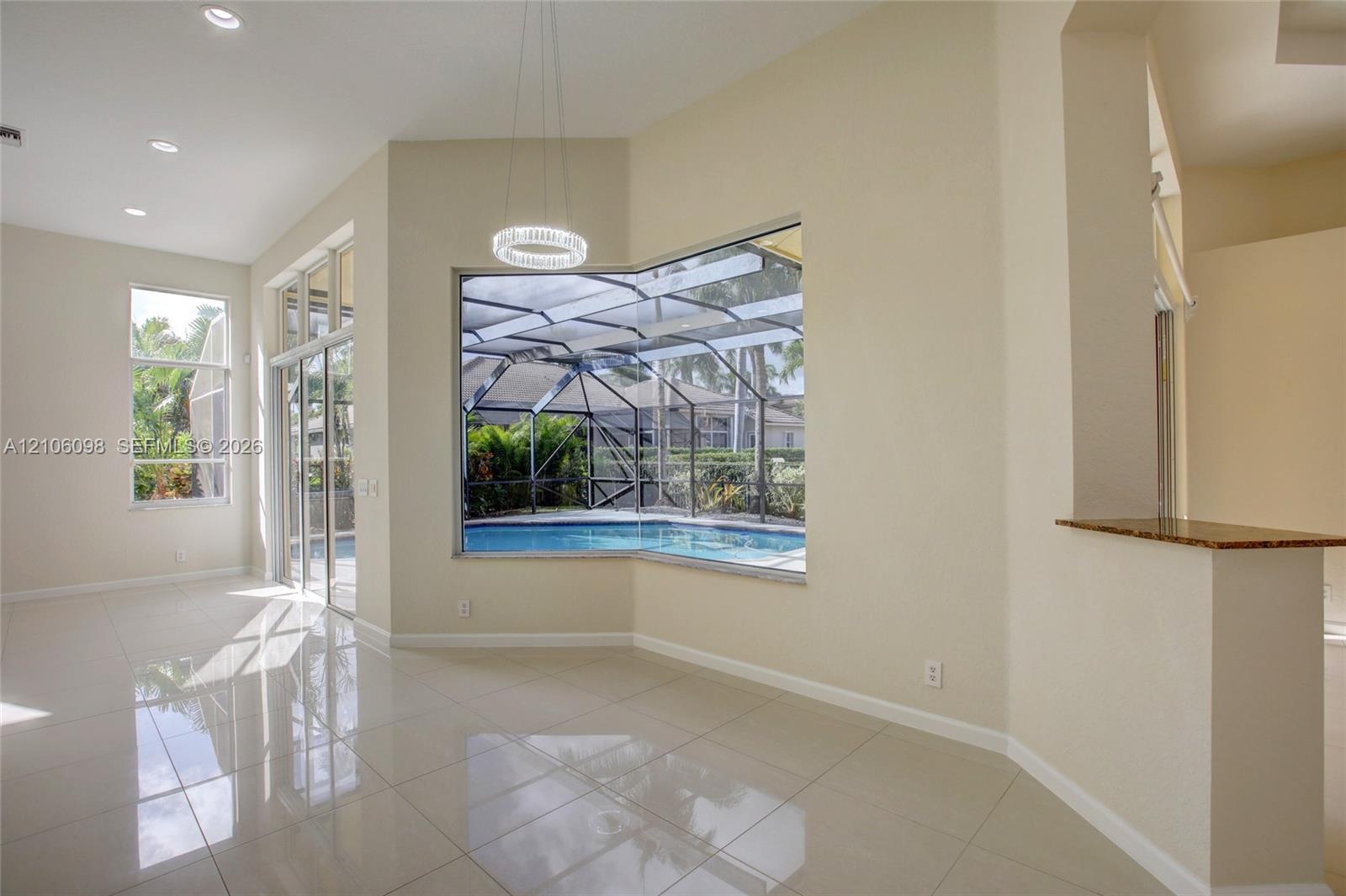 Open-concept interior featuring polished tile flooring, recessed lighting, a built-in stone-surface counter, and large windows encompassing a screened
