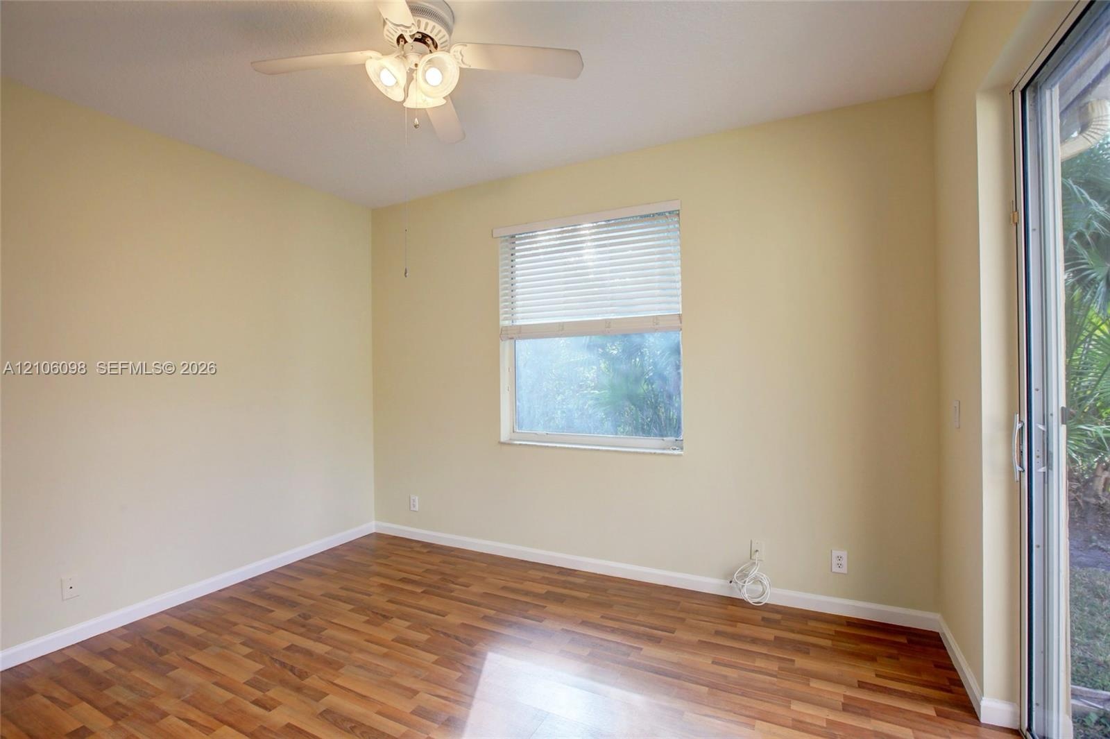 Wood-finish flooring, ceiling fan with integrated lighting, horizontal window blinds, and sliding glass door