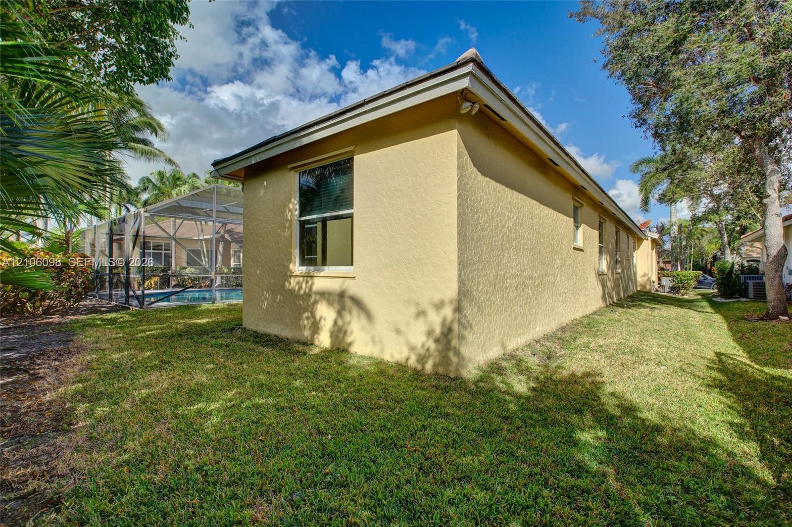 Stucco exterior, screened-in swimming pool enclosure, and mature landscaping