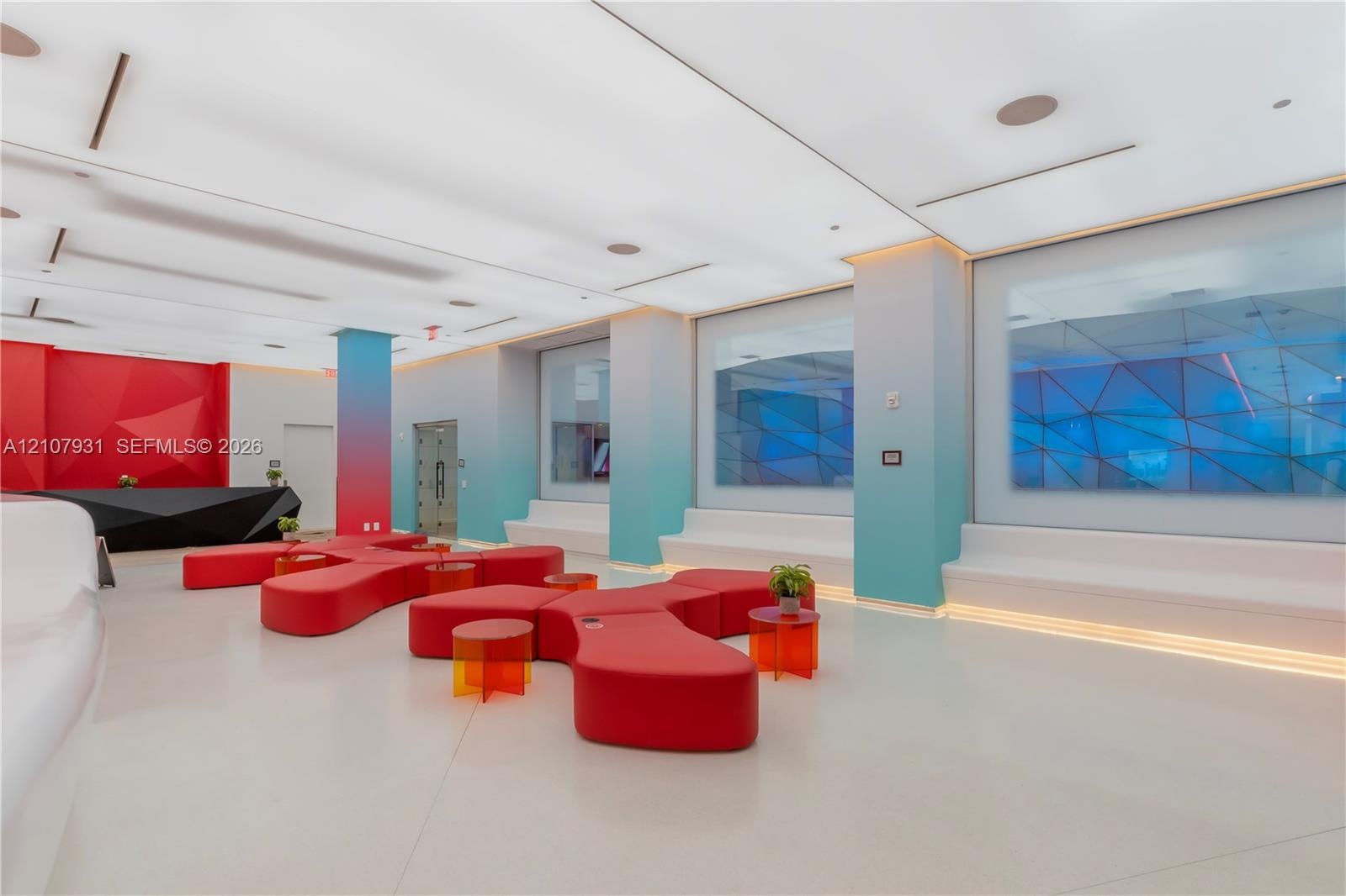 Modern interior space featuring an expansive ceiling with integrated recessed lighting, built-in tiered perimeter seating, smooth-finish flooring, and
