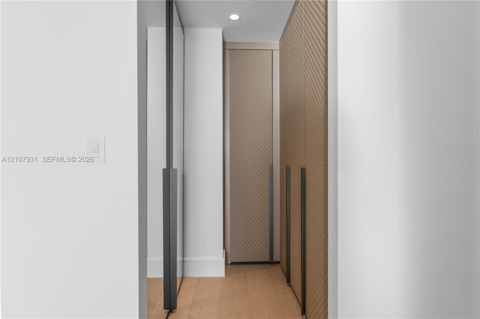 Custom built-in cabinetry with textured, diagonal-patterned detailing, full-length dark metallic hardware, integrated recessed lighting, and wood-fini