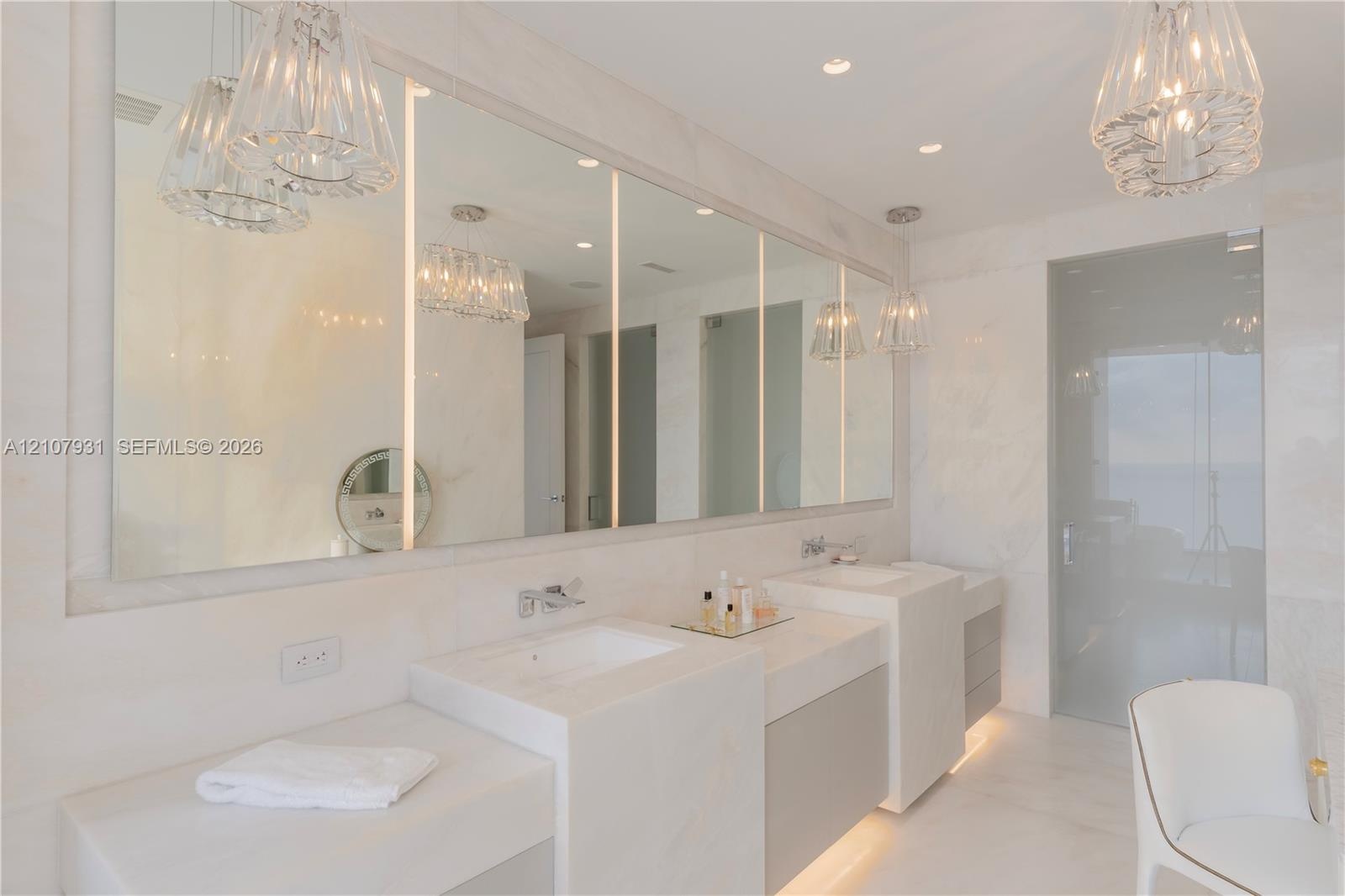 Double vanity featuring integrated rectangular sinks, stone countertops, full-width mirror with vertical LED lighting, recessed ceiling lighting, and 