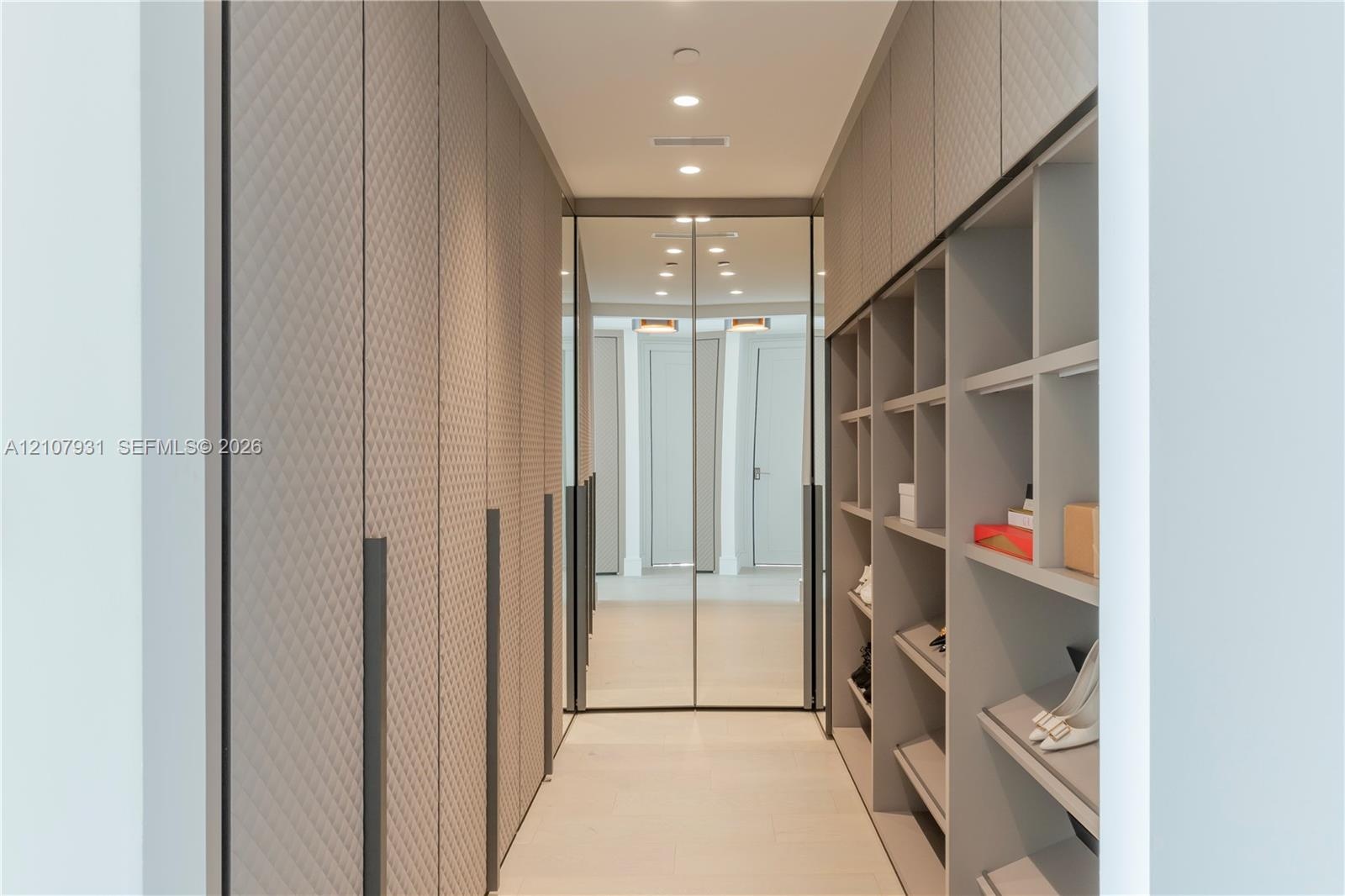 Custom storage solution featuring floor-to-ceiling cabinetry with textured diamond-patterned doors, integrated full-height mirrors, extensive open she