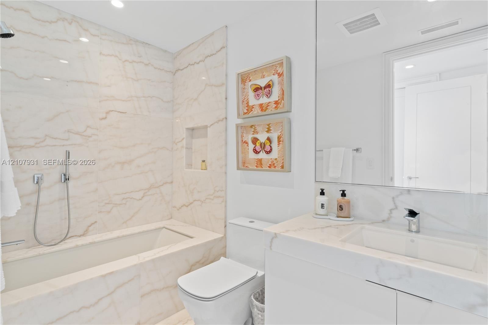 Full-height slab-stone wall surround, integrated recessed shower niche, modern white vanity with matching stone countertop, rectangular undermount sin
