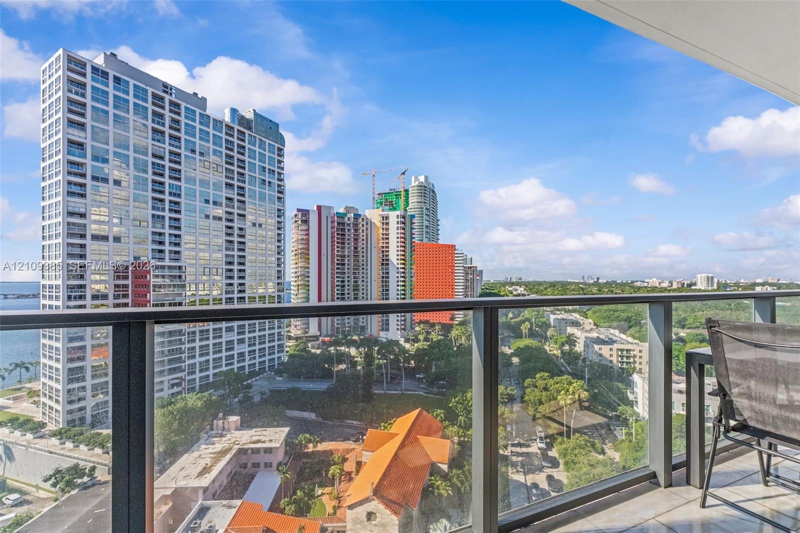 Private balcony featuring metal railing and glass panels with urban and water surroundings