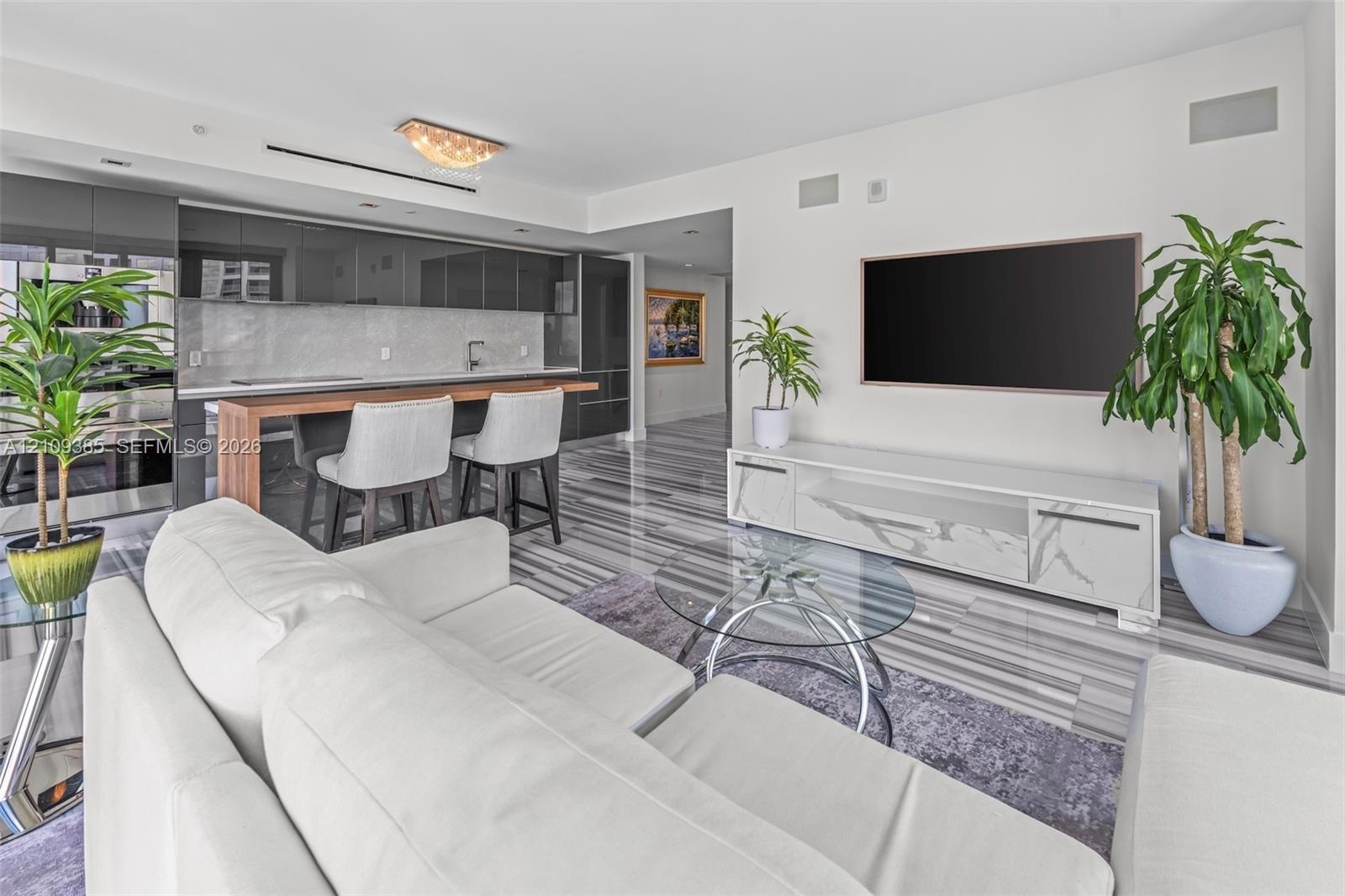 Kitchen featuring high-gloss cabinetry, stone backsplash, and an integrated wood-finish breakfast bar, complemented by polished stone-finish flooring 