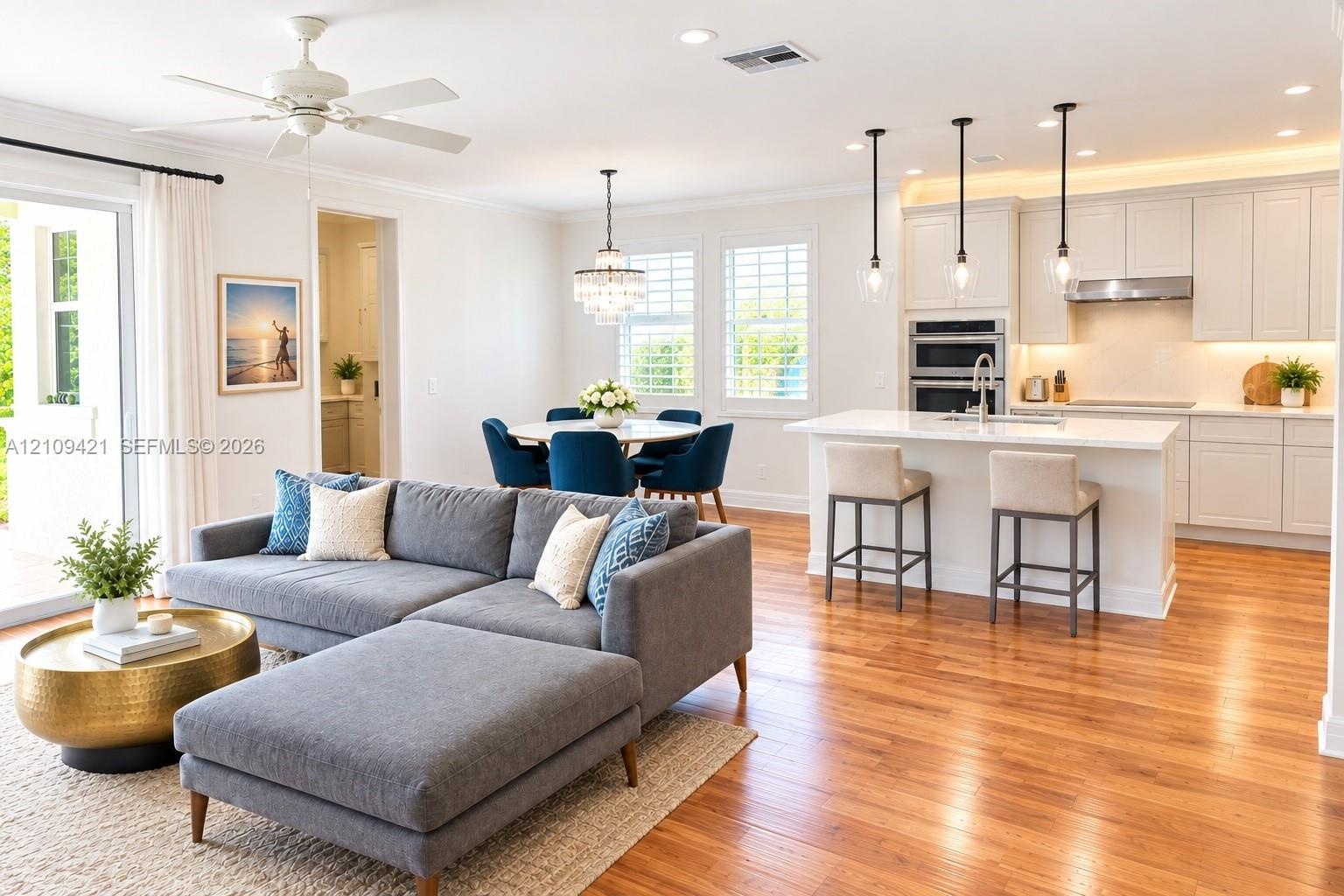 Open-concept interior featuring wood-finish flooring, white cabinetry, an island with stone countertop, stainless steel double wall ovens, and decorat