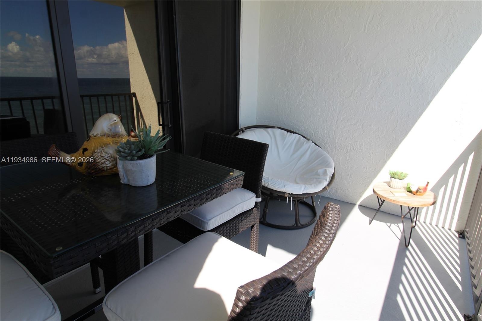 Covered balcony featuring concrete flooring, textured walls, metal railing, and sliding glass door access