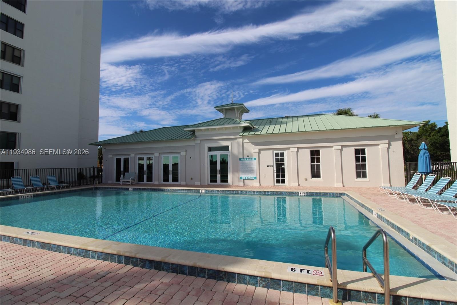 Outdoor swimming pool featuring a paved deck and a clubhouse with a metal roof