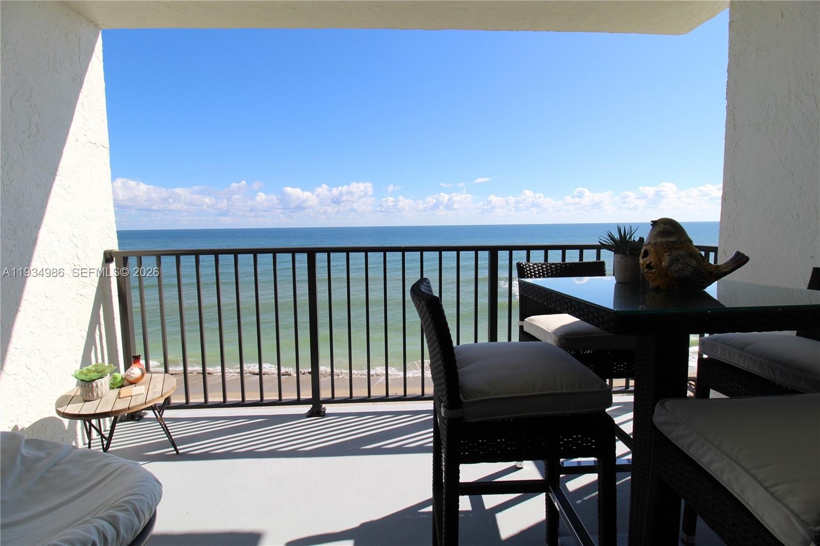 Covered balcony featuring a metal railing and ocean backdrop