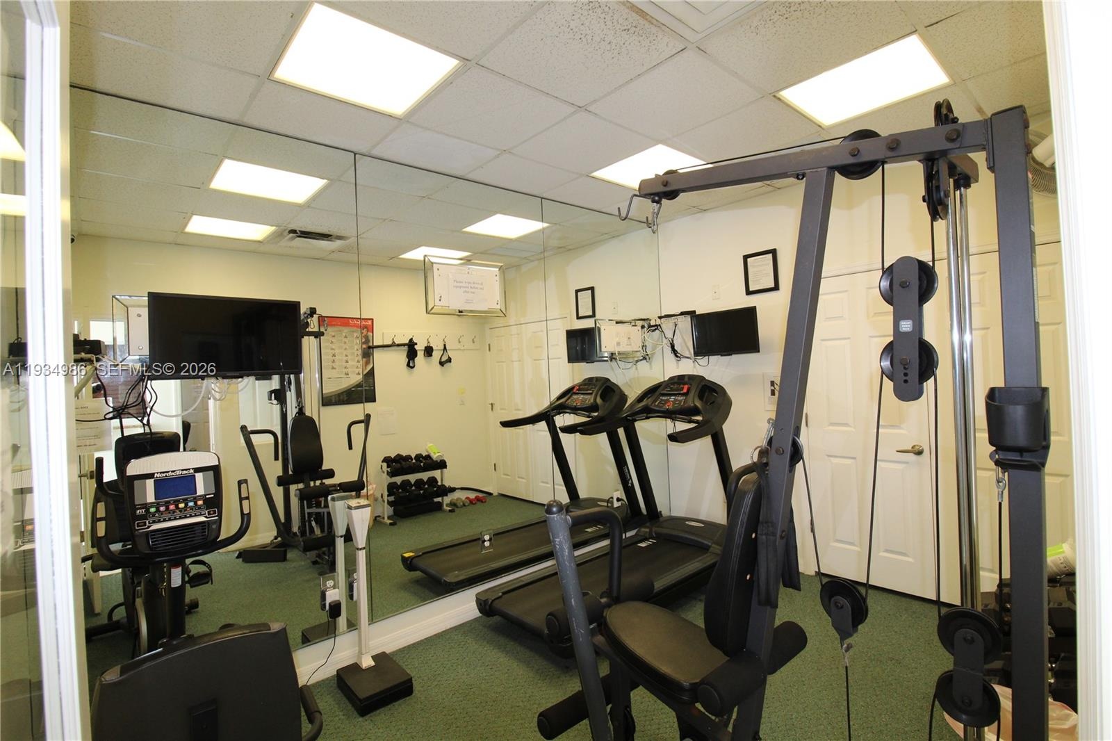 Full-wall mirror, recessed lighting, drop ceiling, and white panel doors