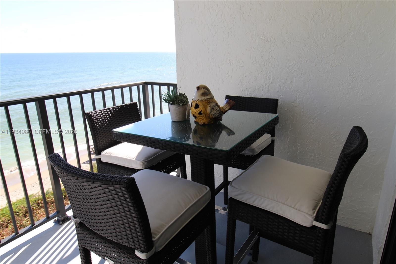 Balcony featuring metal railings and a textured exterior wall finish, overlooking an oceanfront landscape