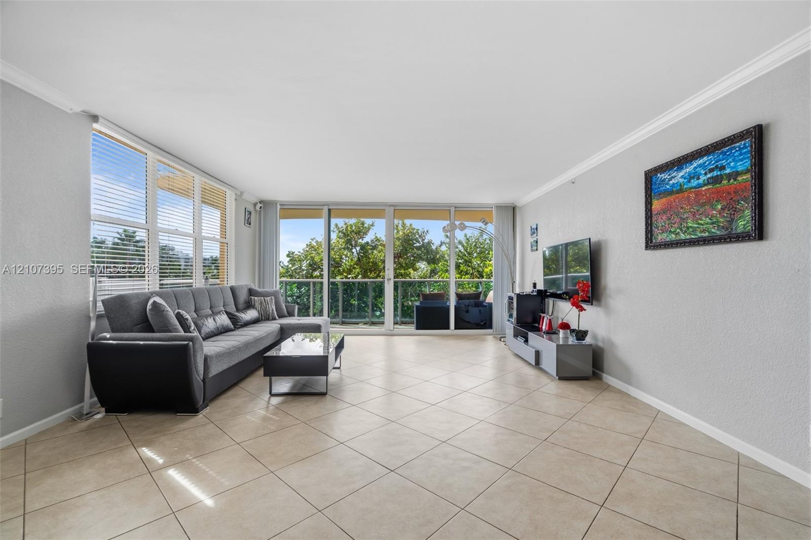 Living area featuring large-format diagonal tile flooring, floor-to-ceiling glass sliding doors, and crown molding