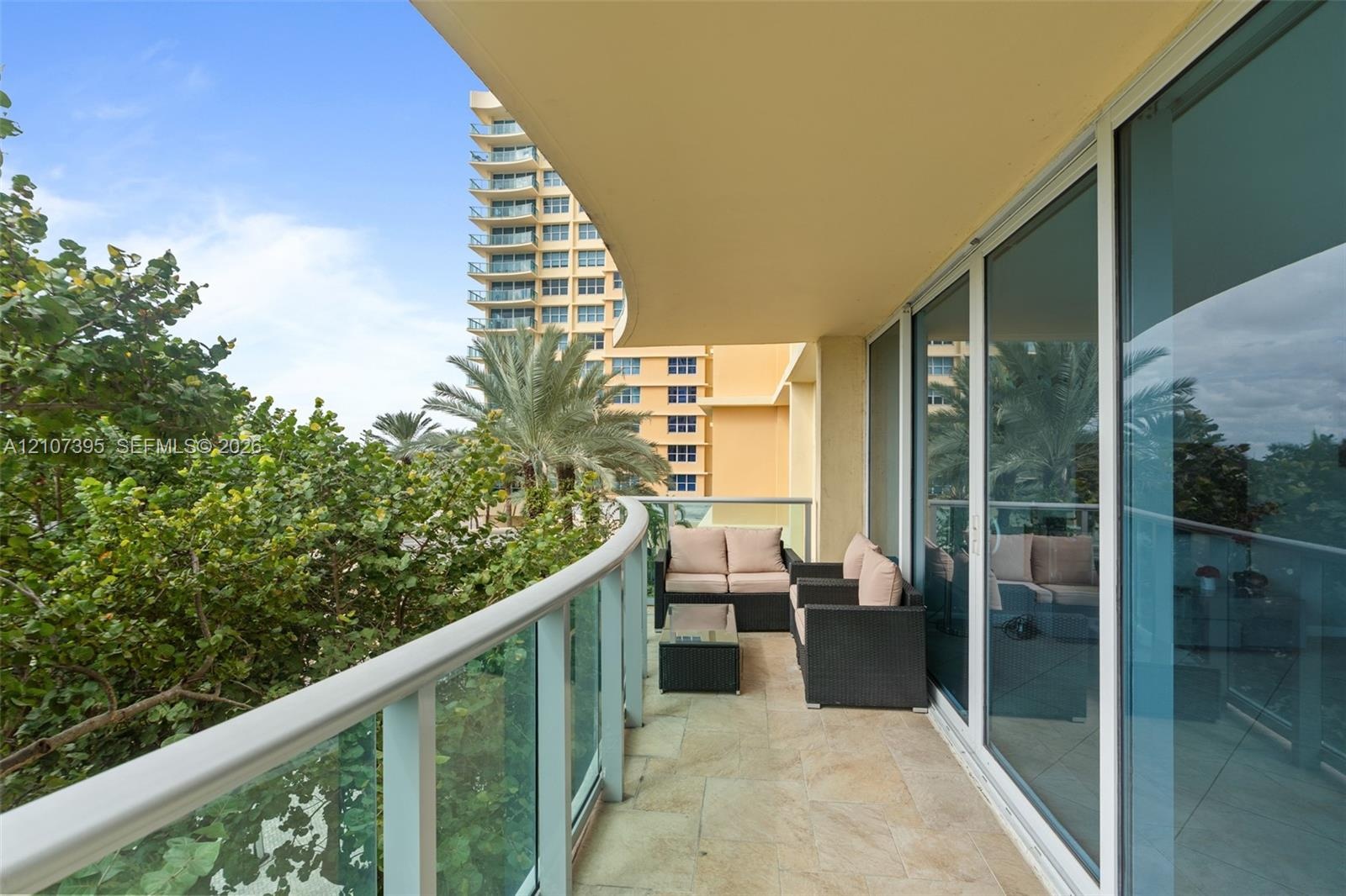 Covered balcony featuring stone flooring, a curved architectural design, and glass-paneled railings