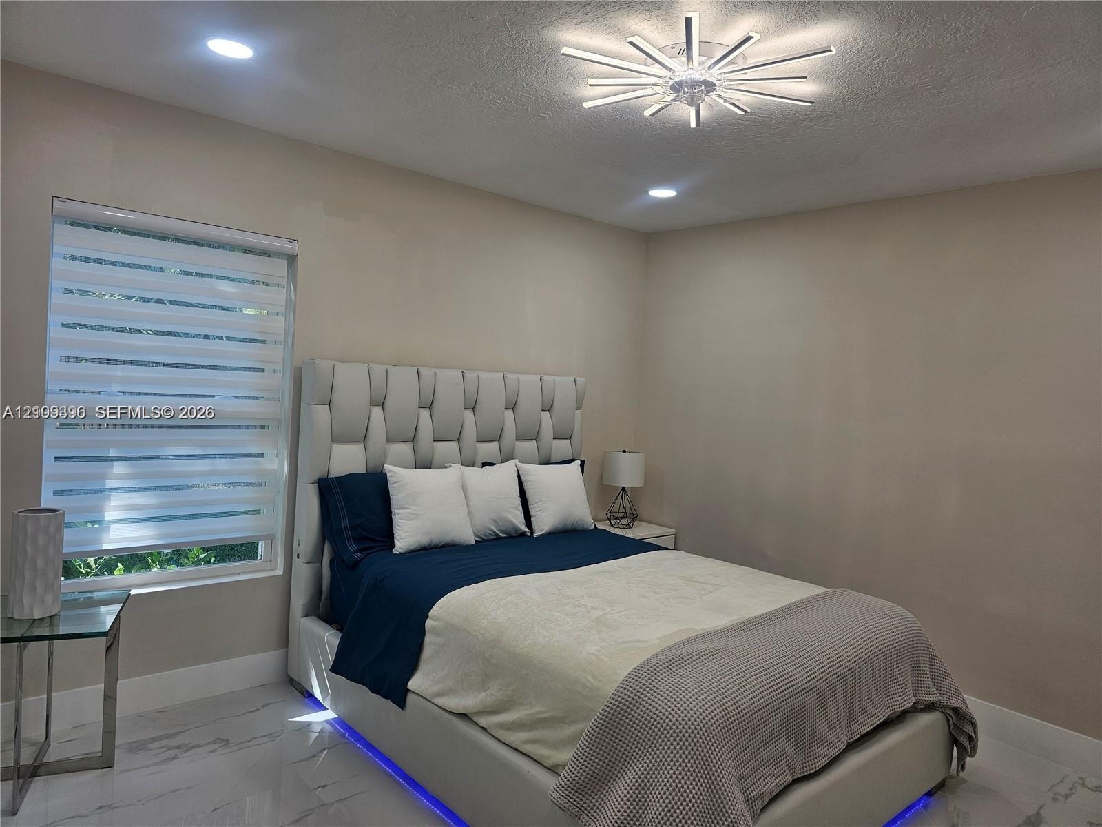 Large-format tile flooring, modern sunburst-style ceiling light fixture, and recessed lighting