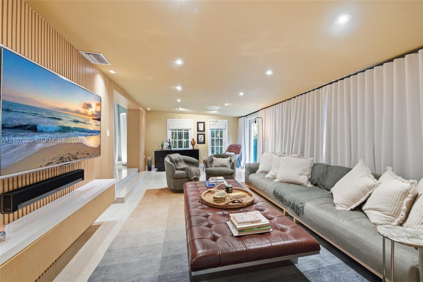 Accent wall featuring vertical wood slat detailing, floating wall-mounted media console, recessed ceiling lighting, and wall-to-wall drapery