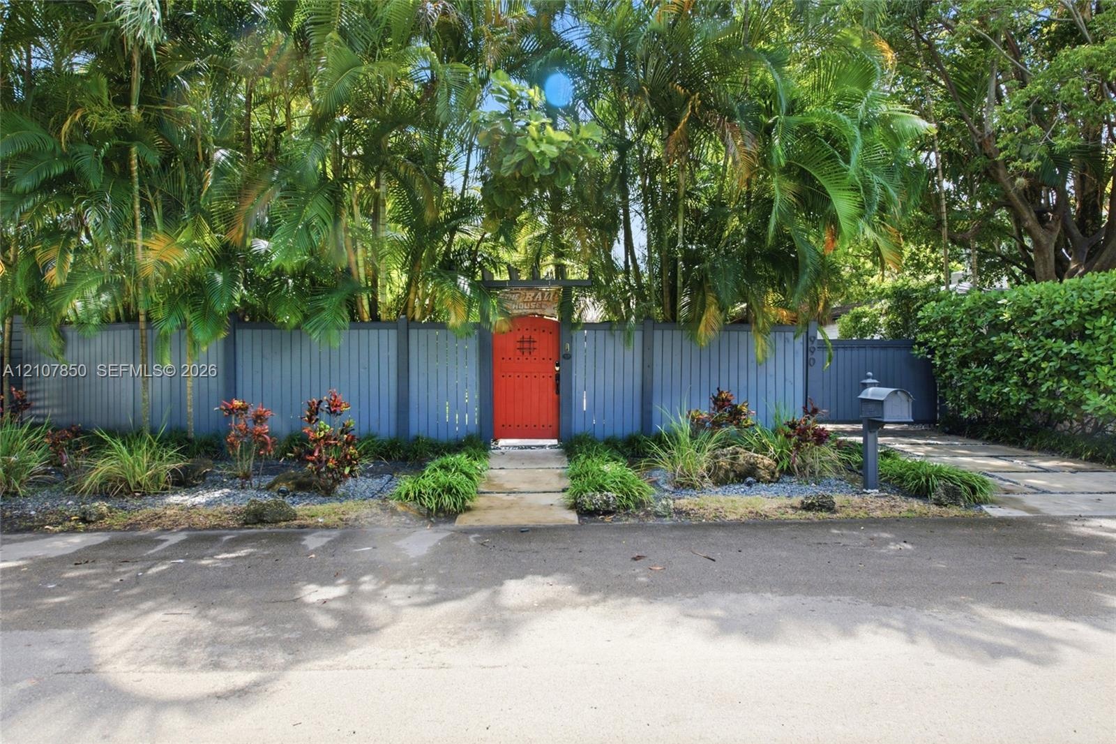 Solid-panel privacy fencing, gated pedestrian entry, concrete paver walkway, and mature landscaping