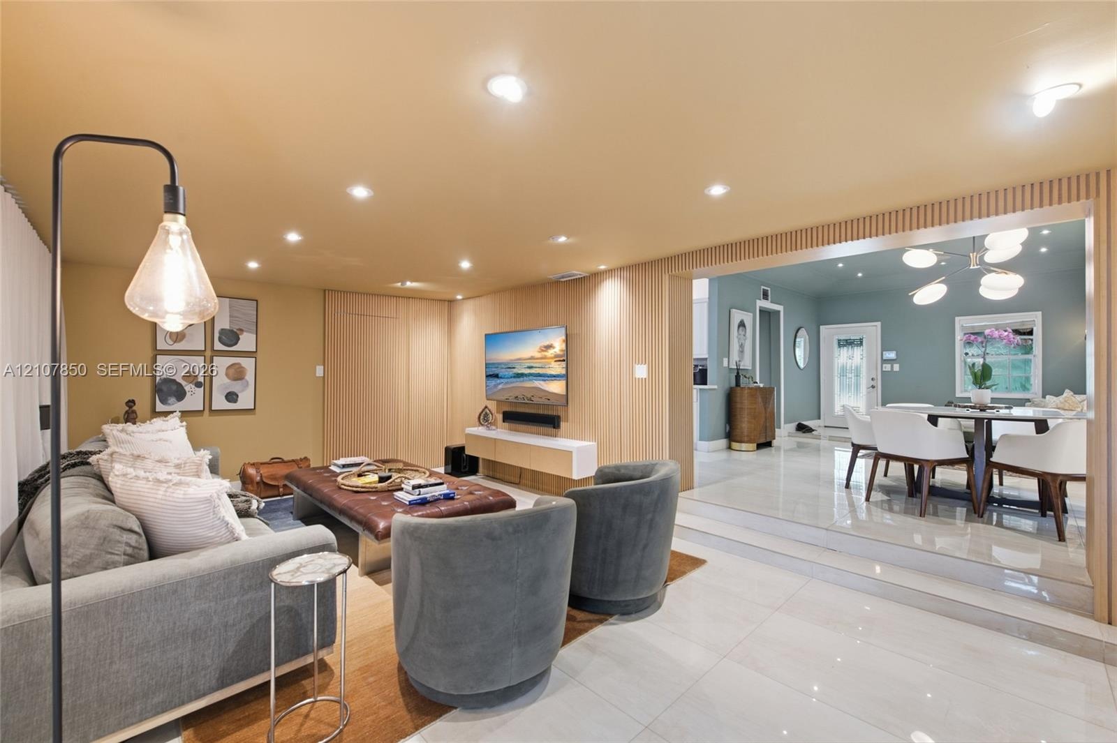 Living space featuring vertical wood slat paneling, recessed lighting, and large-format polished tile flooring