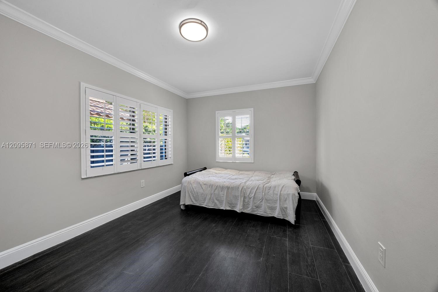 Dark wood-finish flooring, crisp crown molding, and plantation shutters throughout