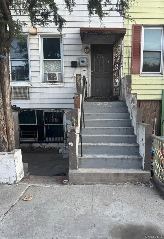 Multi-level exterior featuring horizontal siding, a concrete staircase with metal handrails, and a covered entryway