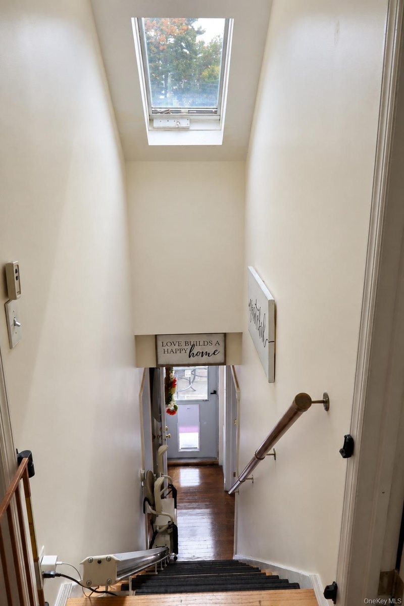 Staircase featuring a skylight and a wall-mounted metal handrail