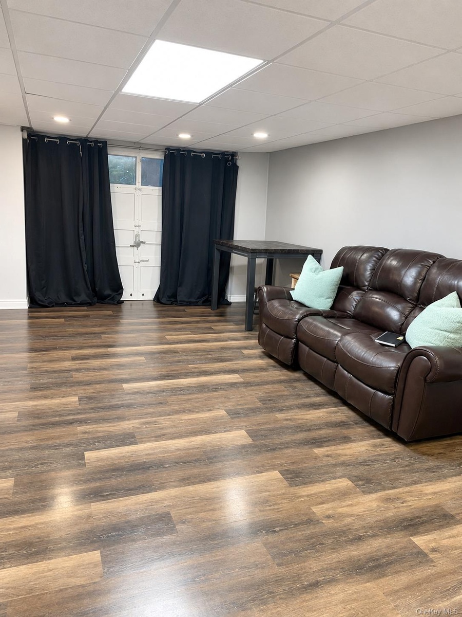 Wood-finish flooring, recessed lighting, and a drop ceiling with a central recessed light panel