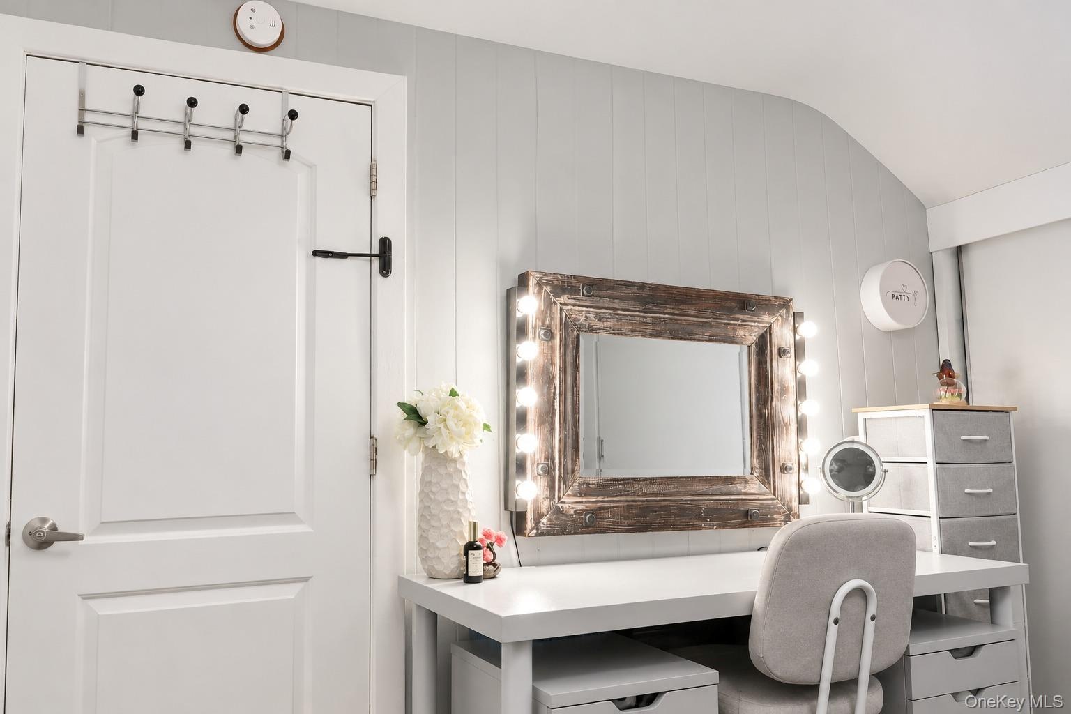 Vertical plank wall paneling and a dedicated vanity station featuring an integrated, wood-frame mirror with perimeter lighting