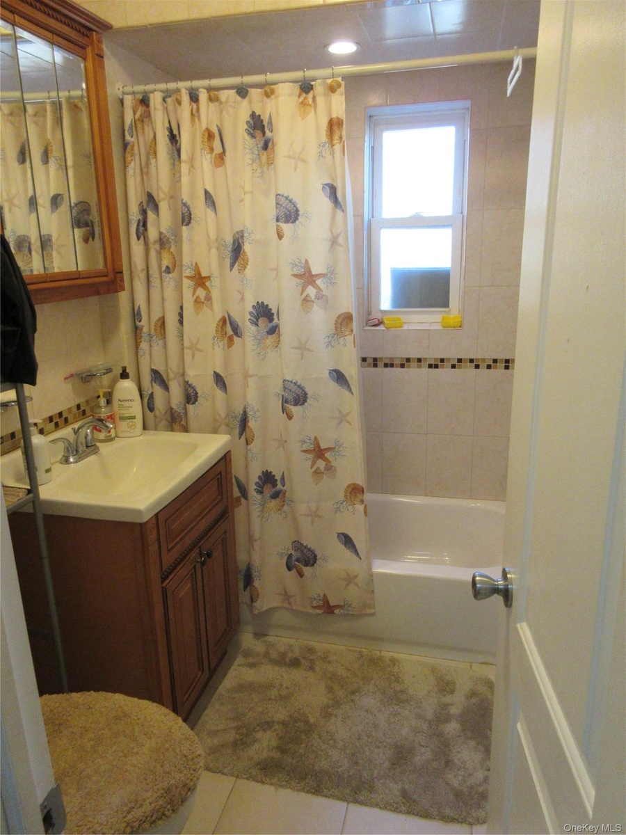 Full bathroom featuring vanity, shower / tub combo, and light tile patterned flooring
