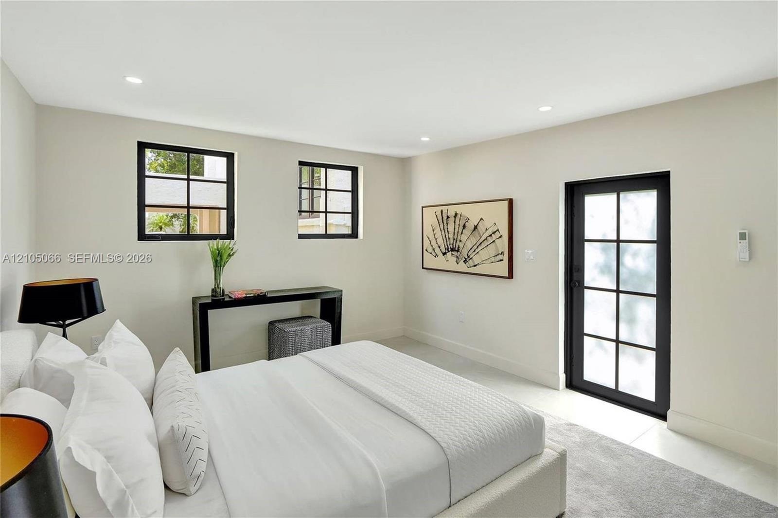 Neutral-toned interior featuring recessed lighting, two multi-pane windows with black frames, and a glass-paneled exterior door with a black frame