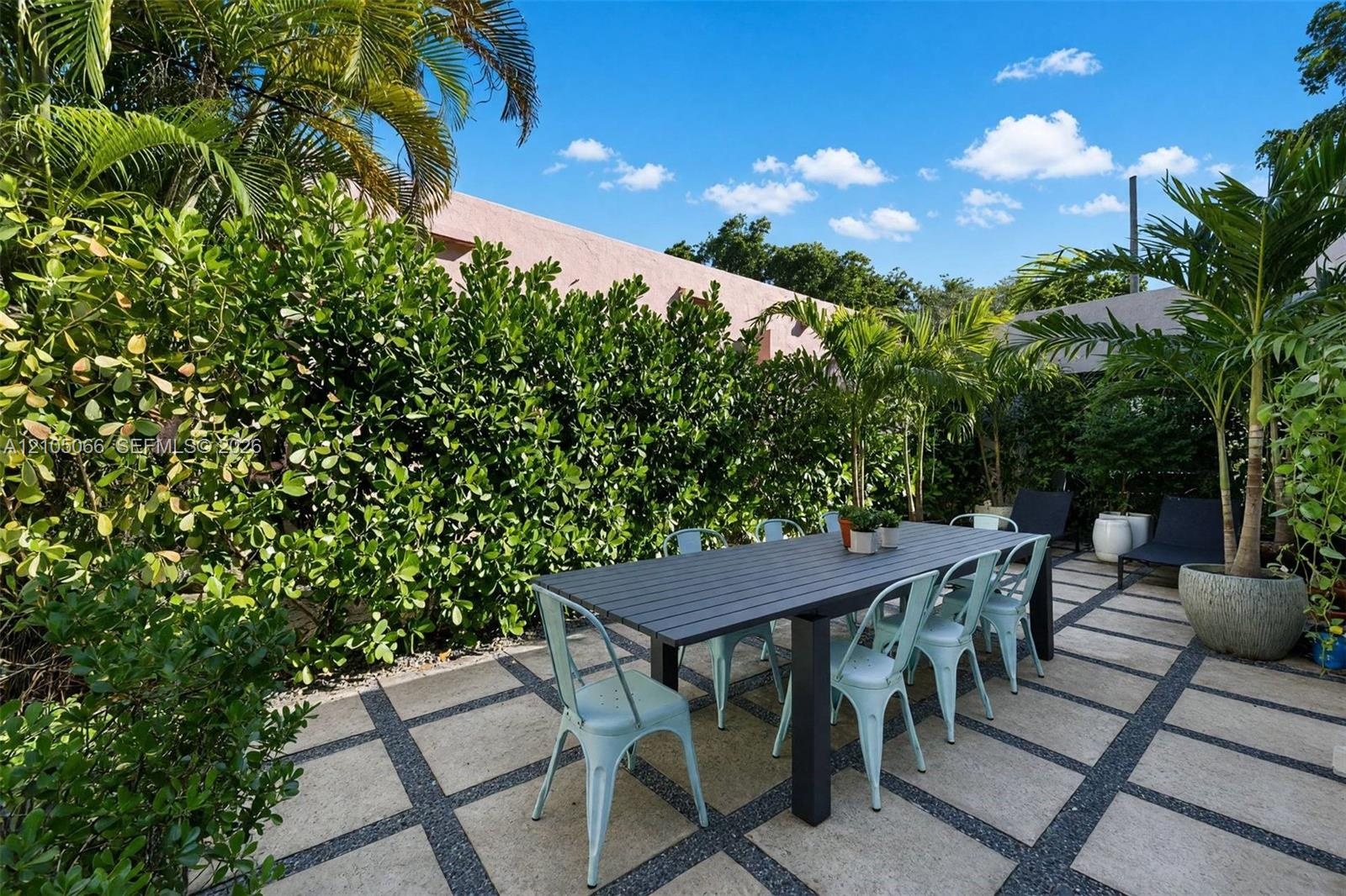 Rear patio featuring large-format stone pavers, geometric gravel inlay, and established perimeter hedges
