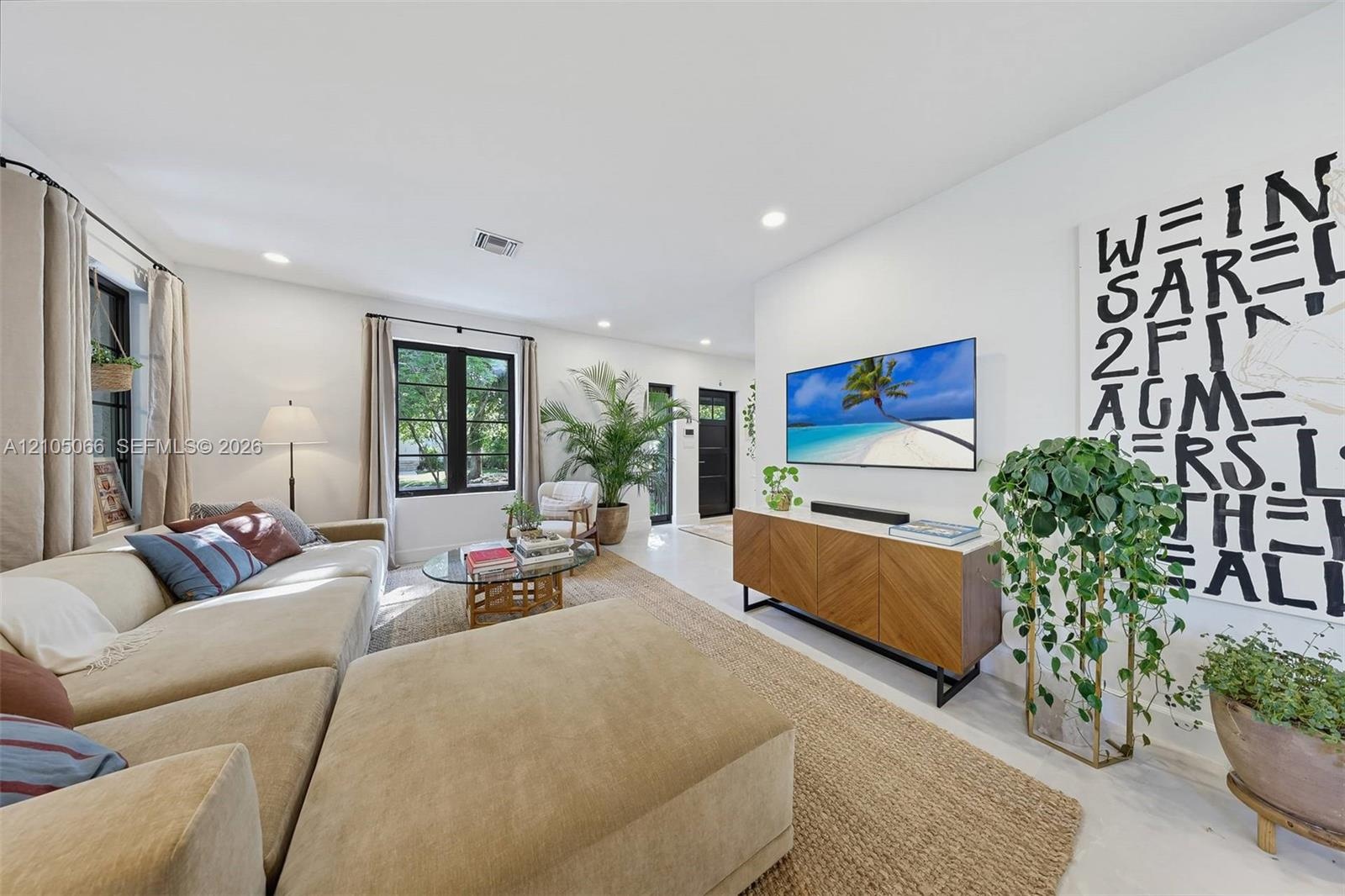 Neutral interior space featuring high ceilings, black-framed multi-pane windows, and light-toned flooring