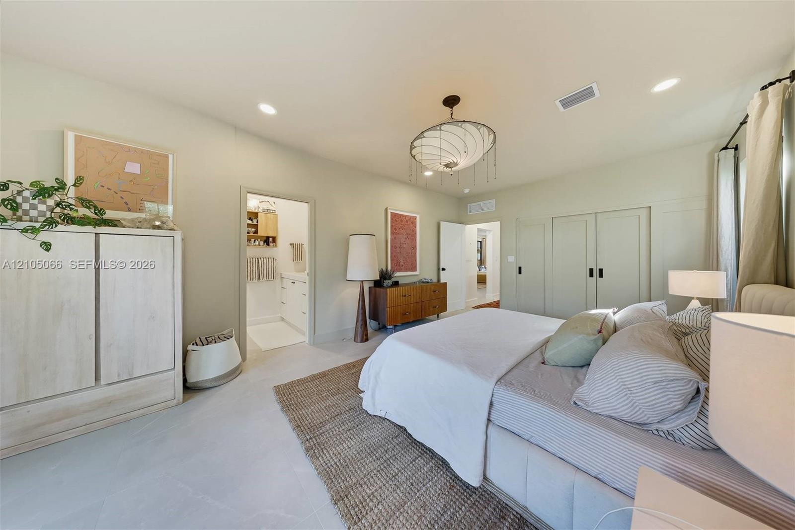 Bedroom featuring light-toned large-format tile flooring, recessed lighting, a modern multi-tiered chandelier, and floor-to-ceiling built-in cabinetry