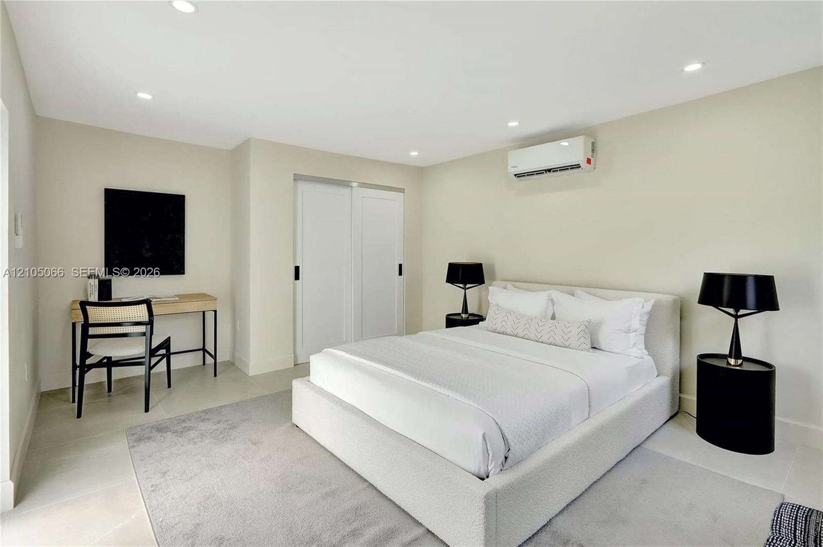 Neutral-toned interior featuring recessed lighting, a wall-mounted climate control unit, and double sliding closet doors