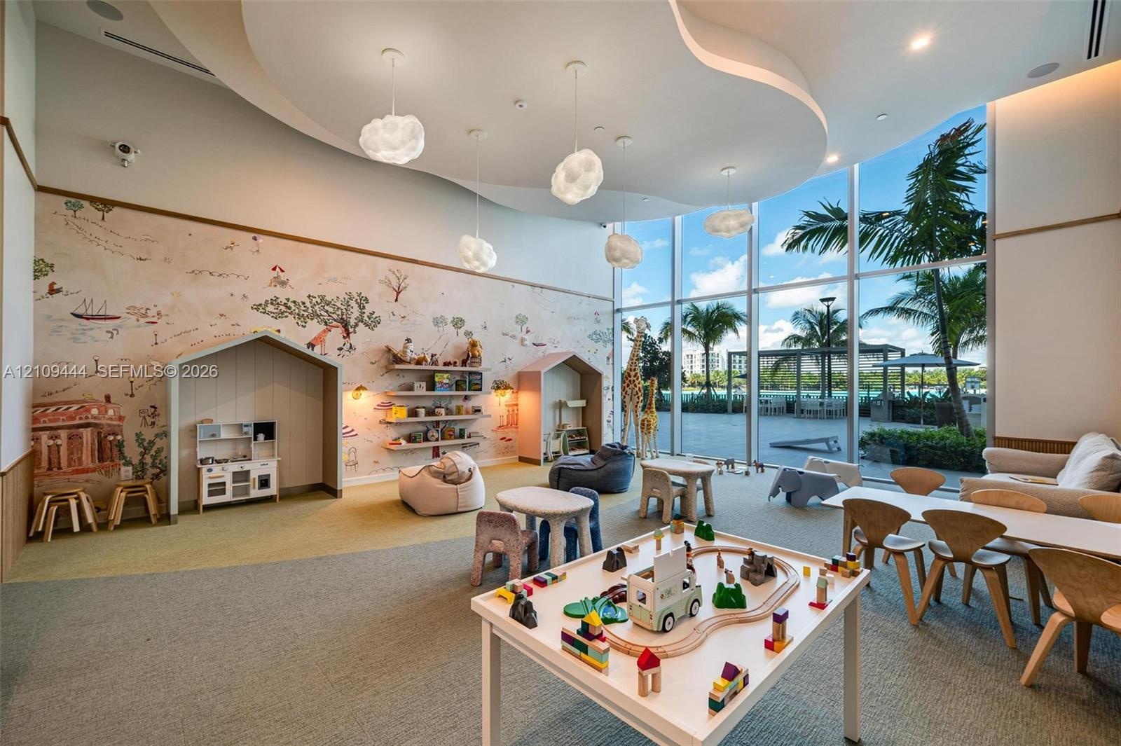 Floor-to-ceiling windows, custom built-in wall alcoves, decorative wall mural, sculpted tray ceiling with recessed lighting, and suspended cloud-style
