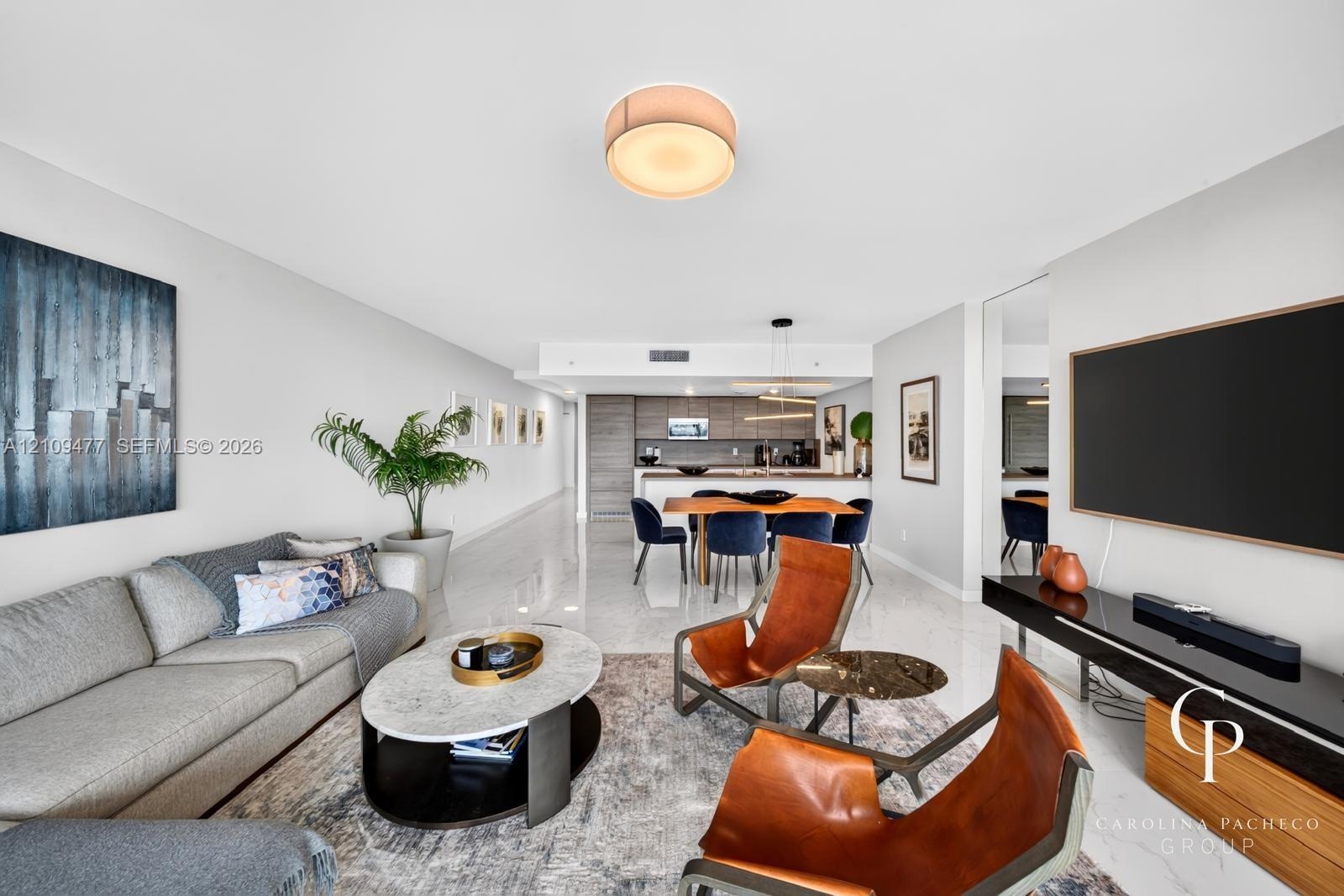 Open-concept living space featuring high-gloss tile flooring, recessed lighting, neutral wall finishes, and integrated cabinetry