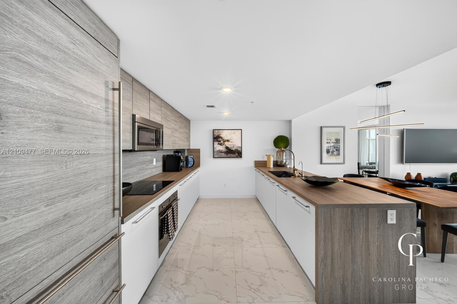 Kitchen featuring custom cabinetry with horizontal wood-grain finish, contrasting white lower cabinets, extended peninsula with wooden waterfall count