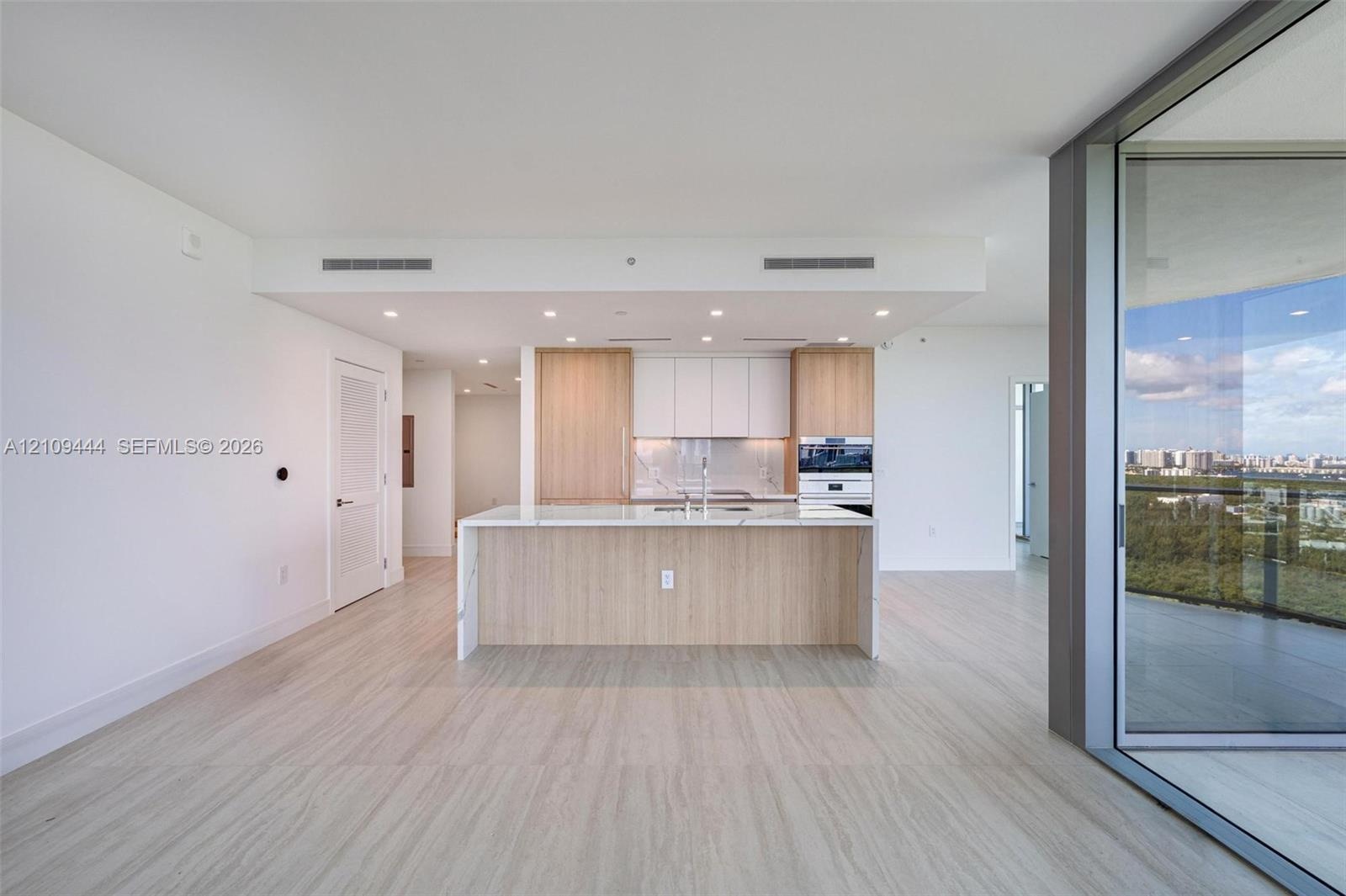 Kitchen featuring an island with stone-finish countertop, wood-finish cabinetry, built-in stainless steel wall oven, recessed lighting, and expansive 