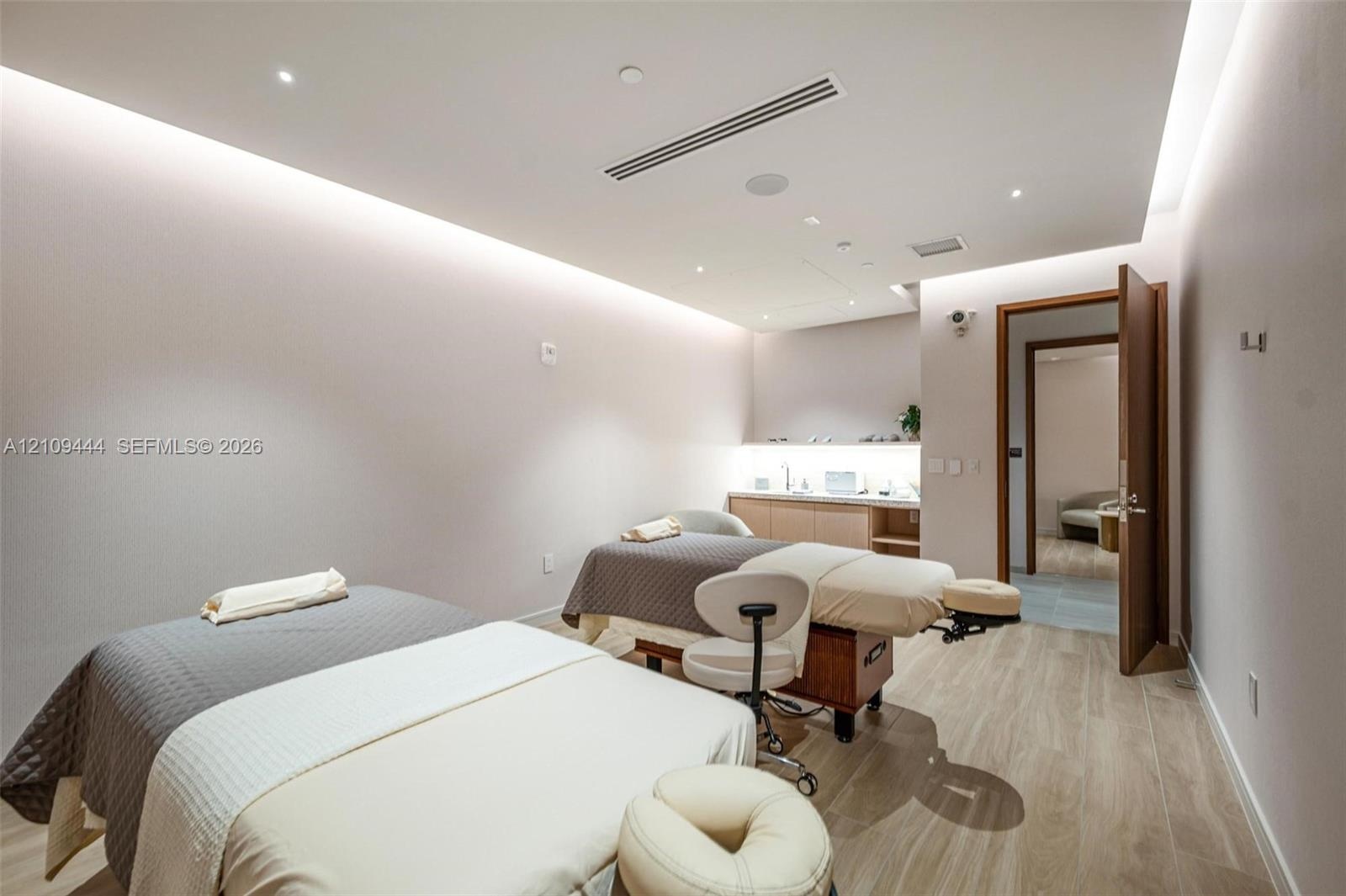 Interior room featuring wood-finish flooring, recessed ceiling lighting with perimeter cove illumination, and built-in cabinetry with integrated under