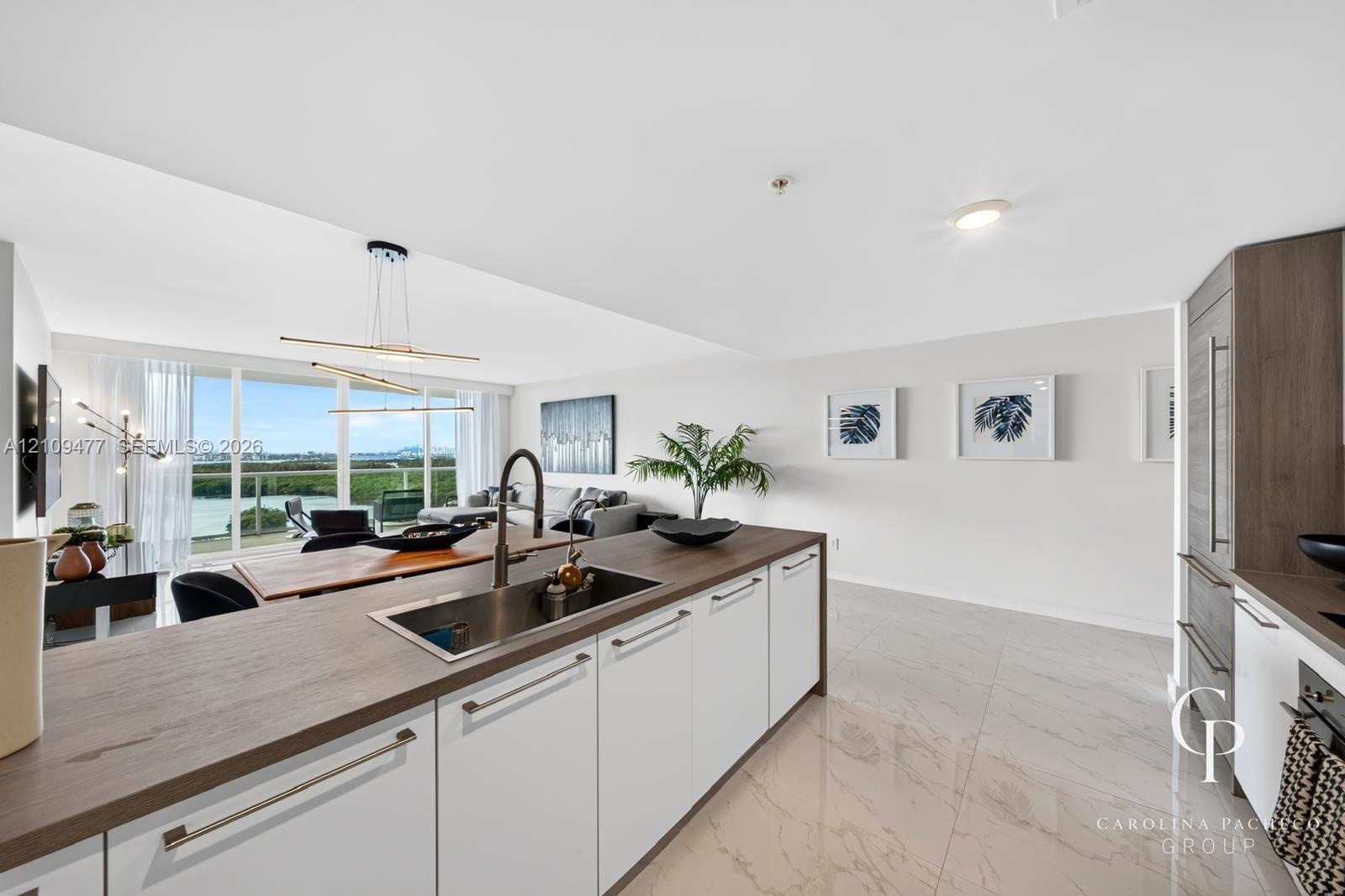 Kitchen featuring a central island with a wood-finish countertop, stainless steel undermount sink, high-arc faucet, white cabinetry with horizontal ha