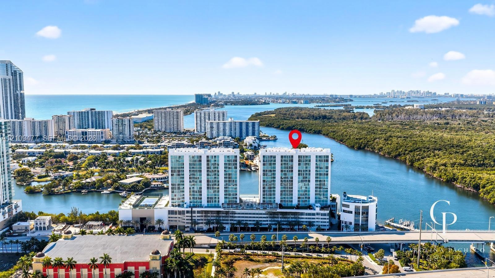 Aerial perspective of a high-rise residential building situated along a waterway, featuring coastal surroundings, expansive water access, and proximit