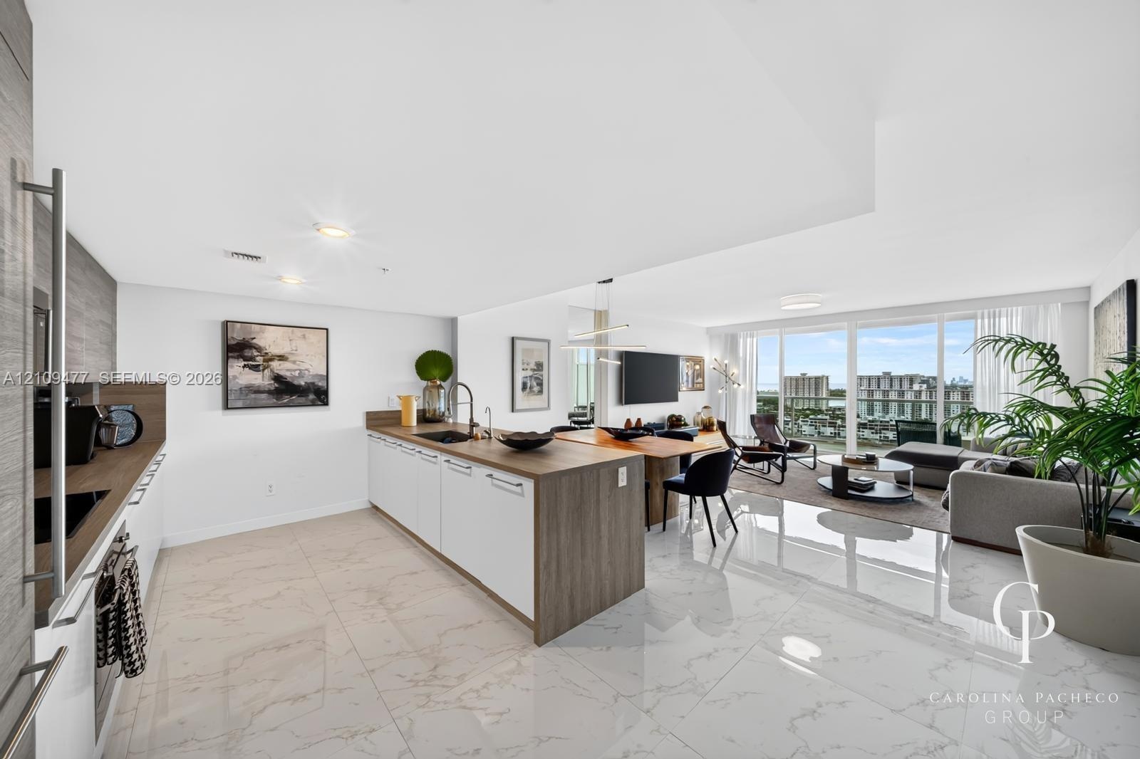 Open-concept kitchen featuring an island with wood-finish cabinetry, white flat-panel lower cabinets, stone-surfaced countertops, and polished tile fl