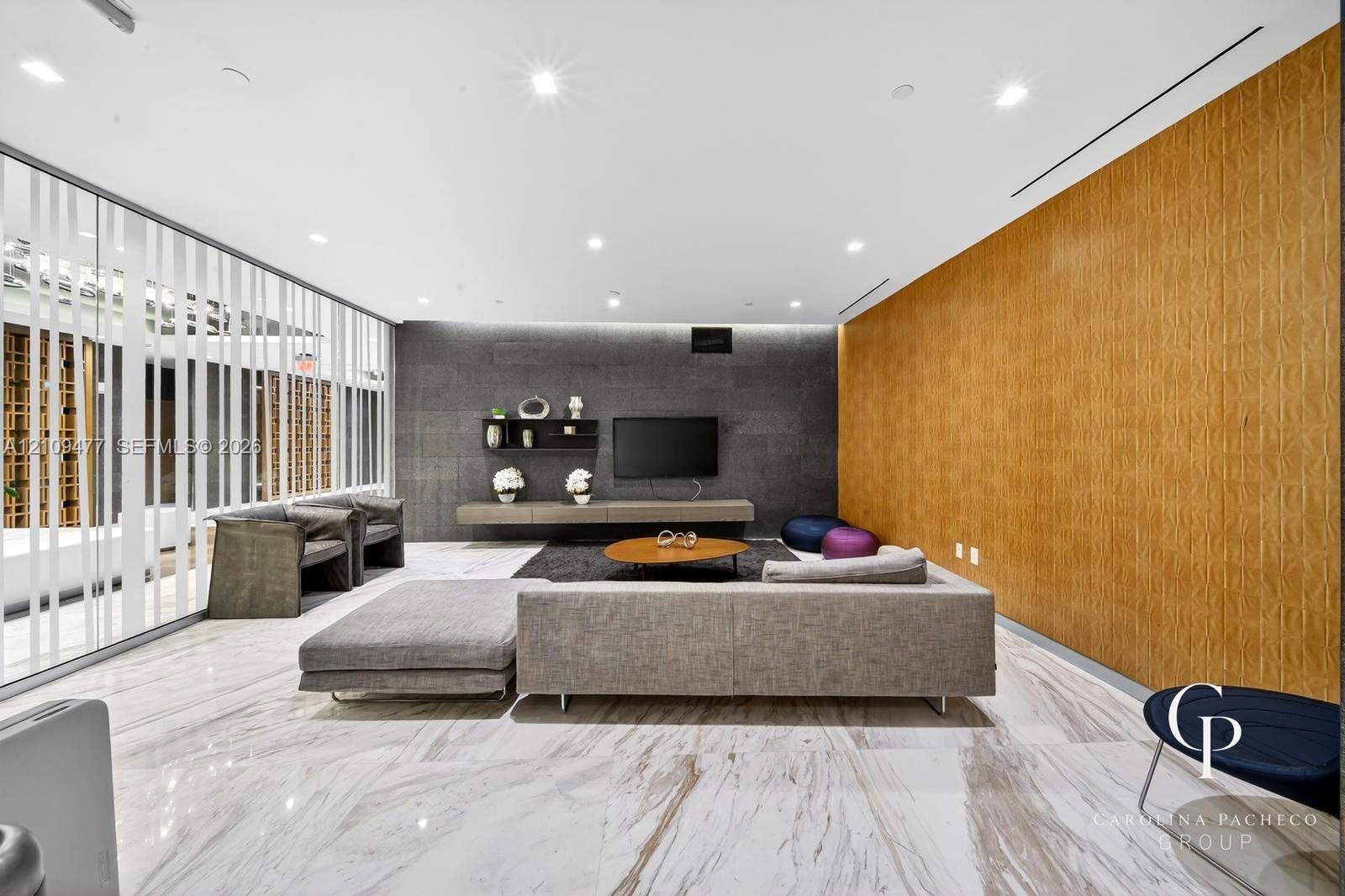 Large-format polished stone flooring, custom wood-paneled accent wall, dark stone-clad feature wall, floating built-in cabinetry, and full-height glas