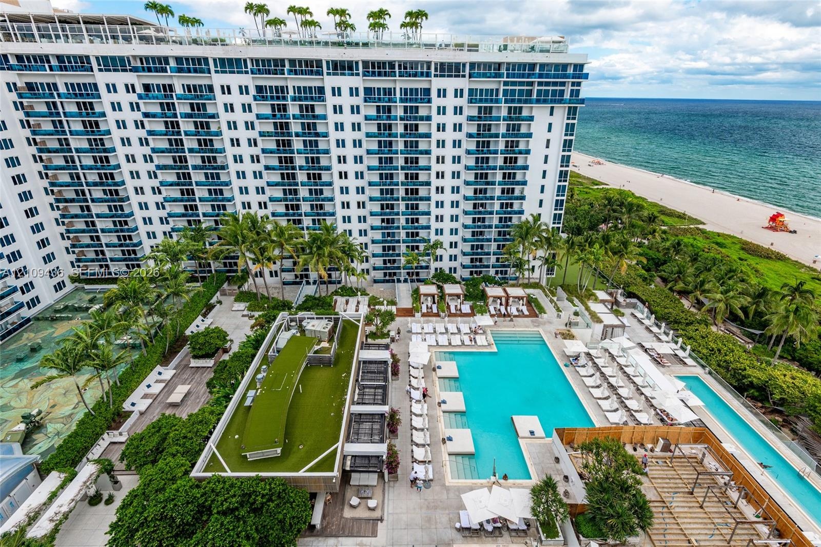 Multi-story beachfront high-rise featuring expansive exterior balconies, resort-style swimming pools, landscaped sundecks, and direct proximity to the