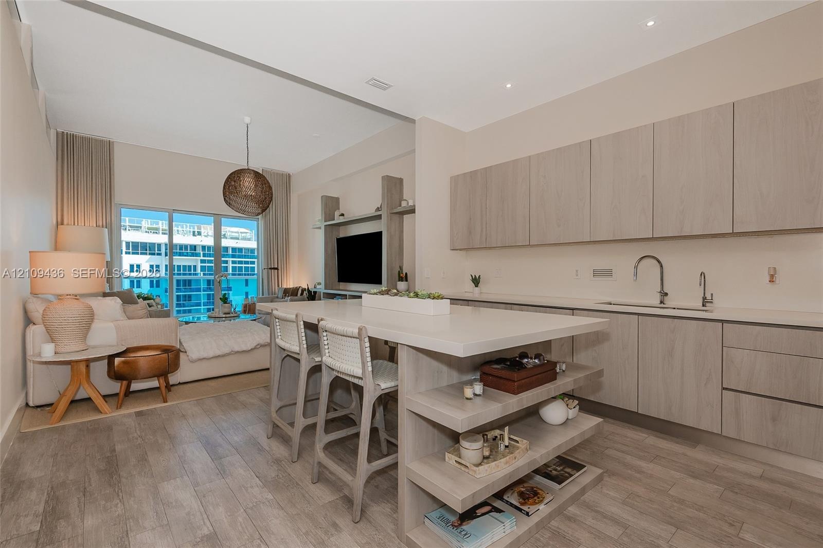 Open-concept kitchen featuring wood-finish cabinetry, a central island with integrated shelving, quartz countertops, wood-finish flooring, and recesse