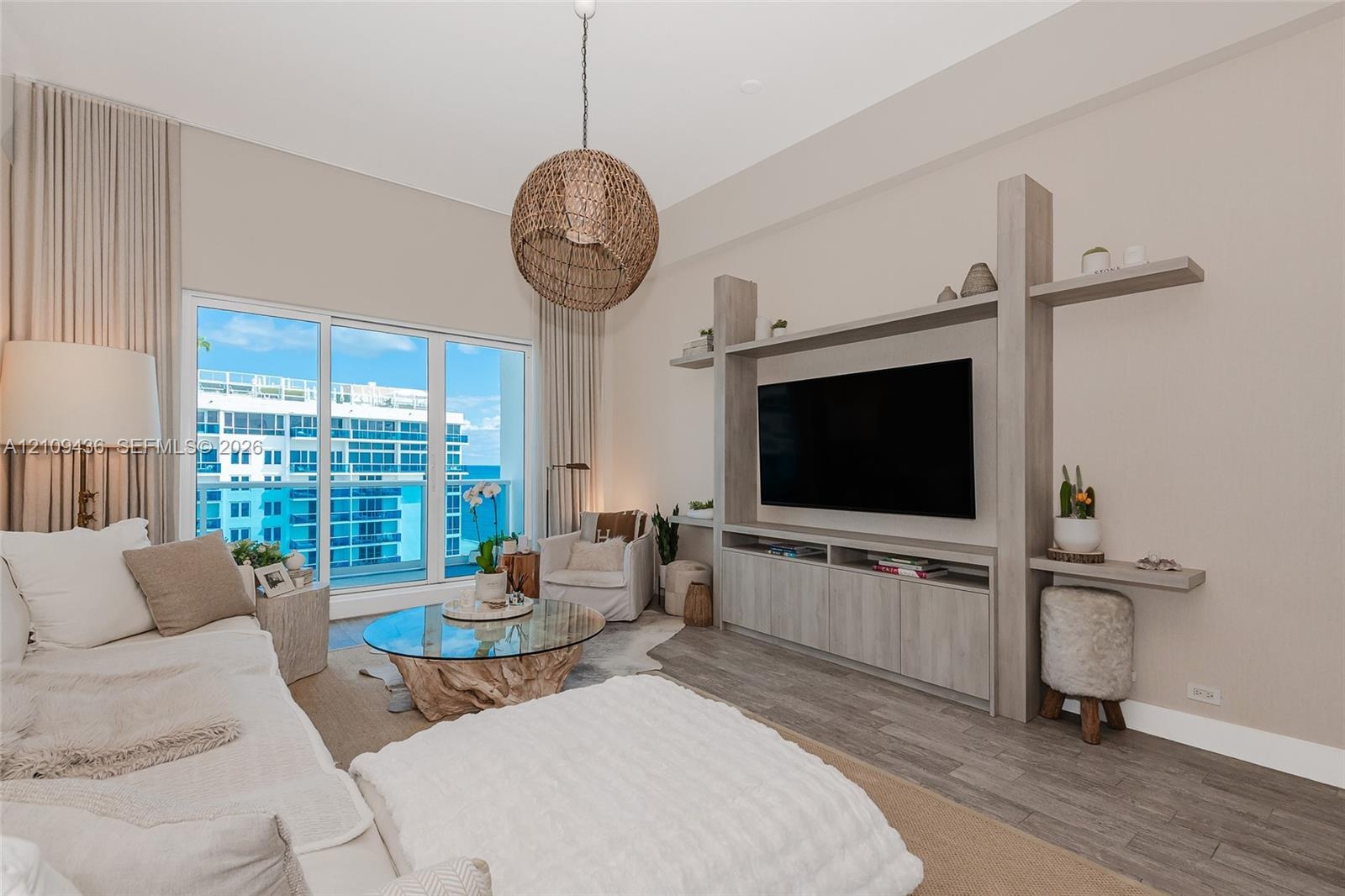 Living area featuring floor-to-ceiling sliding glass doors, custom built-in cabinetry with integrated shelving, and wood-finish flooring