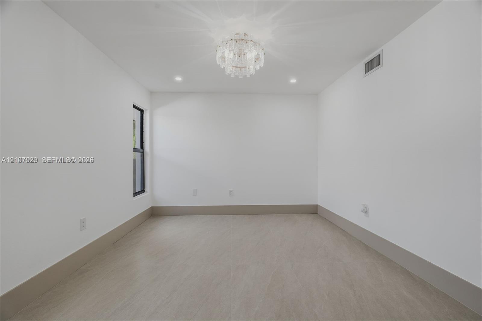 Neutral-toned room featuring a tiered crystal chandelier, wood-finish flooring, recessed lighting, double-panel sliding closet doors, and black-framed