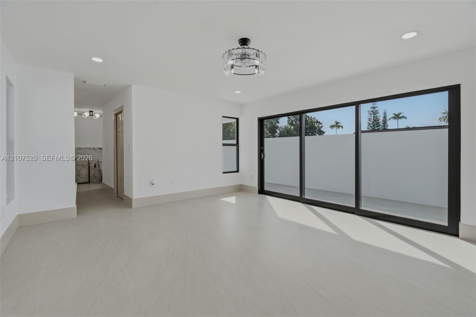 Interior space featuring large-format tile flooring, a two-panel door with matte black hardware, and an elongated porcelain toilet