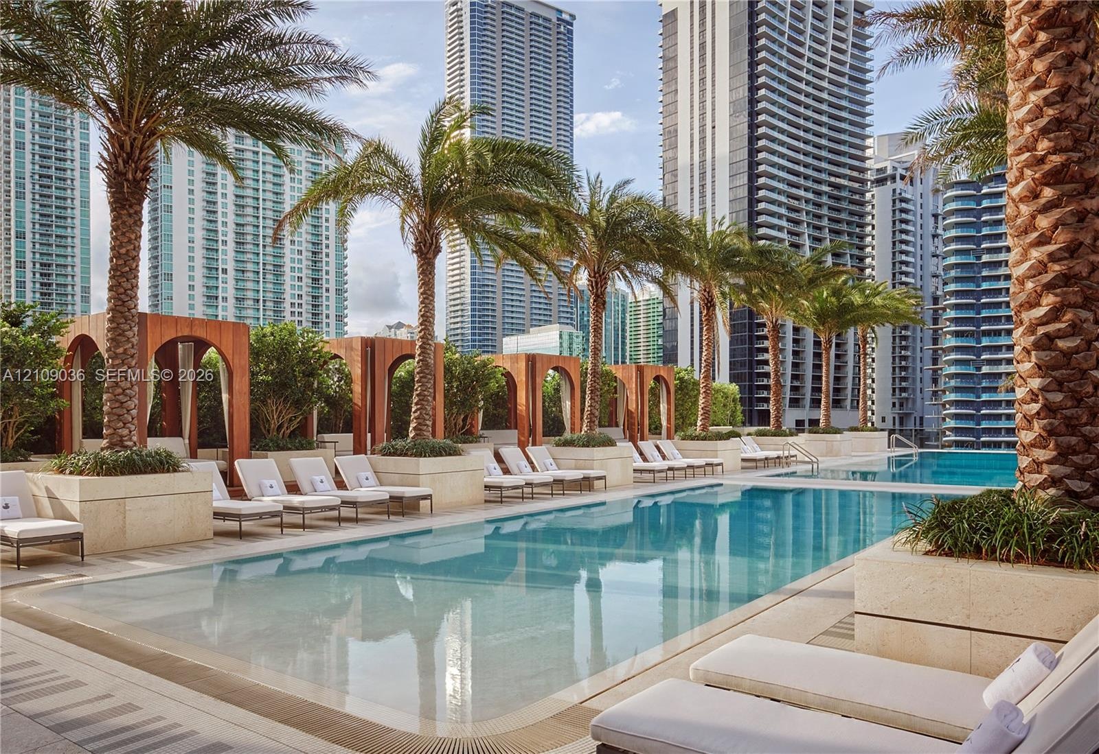 Swimming pool featuring stone-clad planters, integrated arched architectural accents, and palm tree landscaping