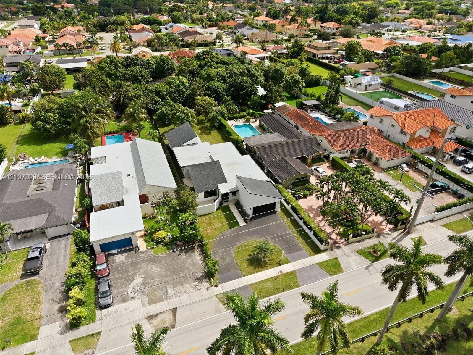 Expansive residential grounds featuring two inground swimming pools, manicured lawn, established perimeter hedging, and mature trees
