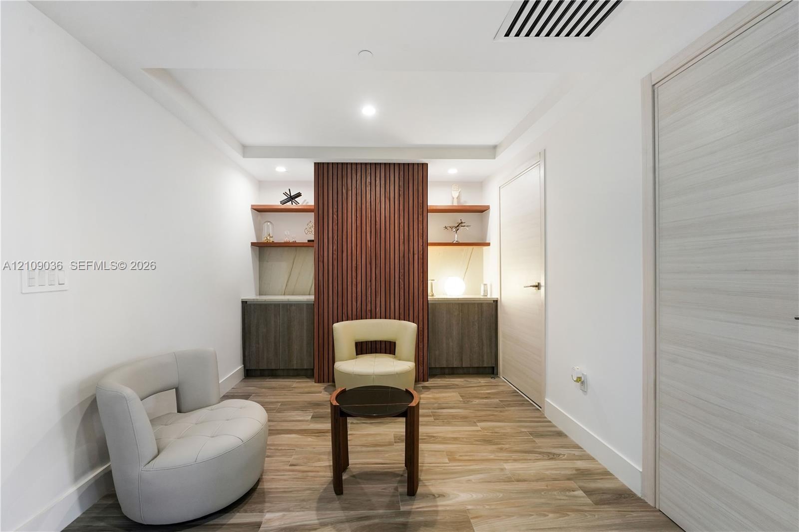 Custom built-in cabinetry with flat-panel doors, vertical slat wood accent feature, integrated floating shelving, recessed ceiling lighting, and wood-